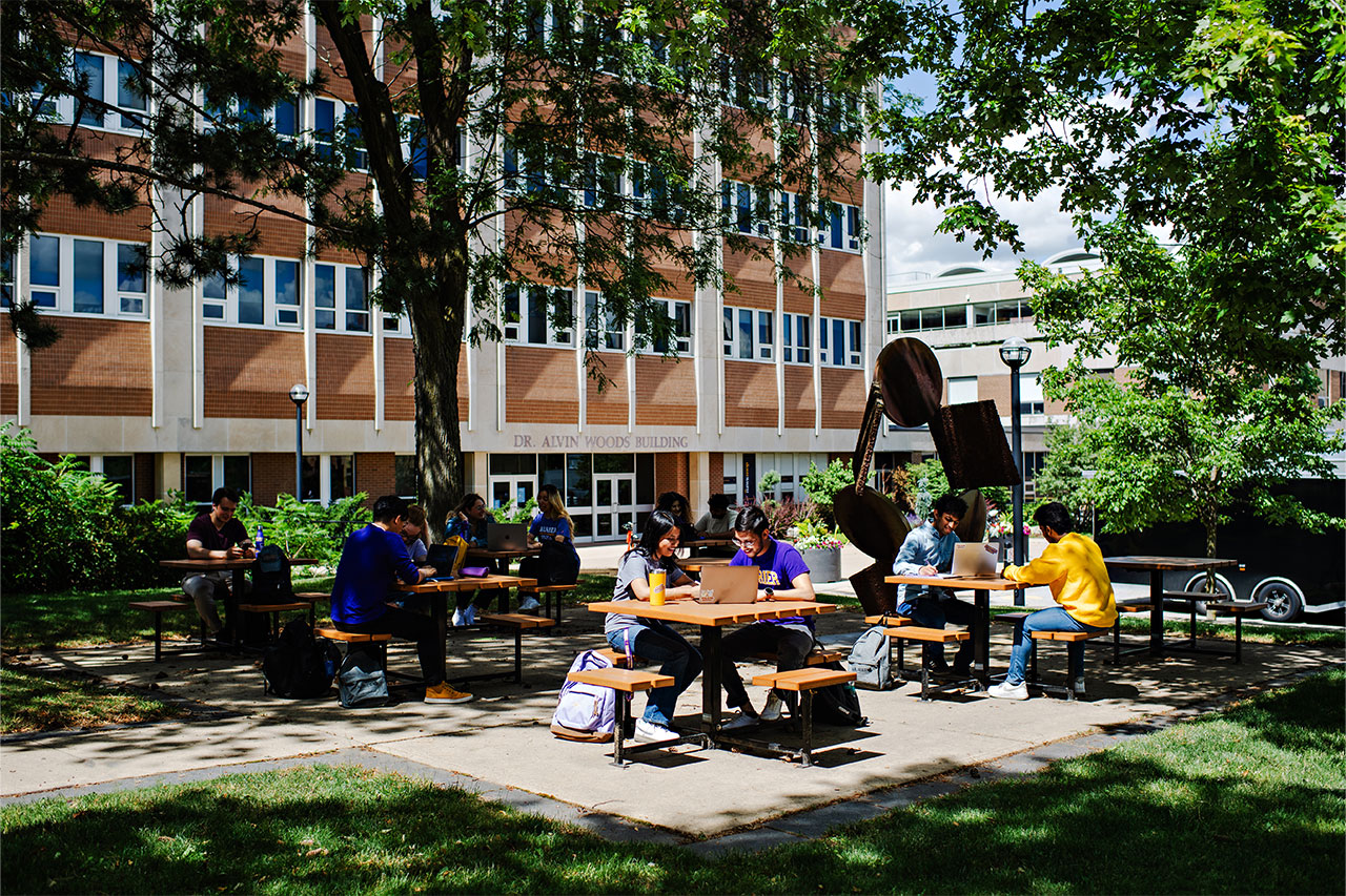 Students sitting in picnic tables outside of DAWB building