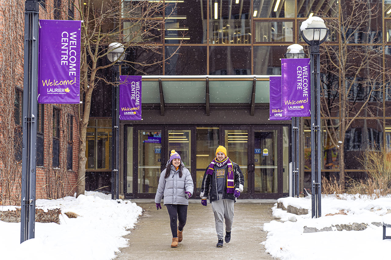 Two students walking in front of Peters Building during Winter