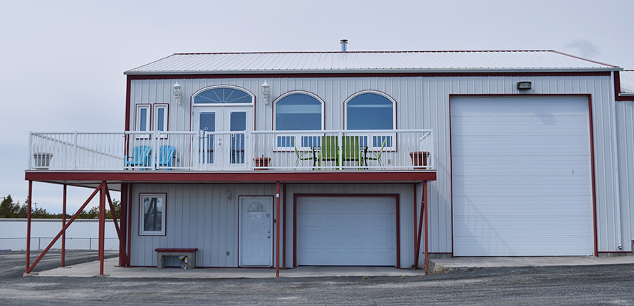 Exterior of a warehouse with two garage doors and a balcony that wraps around the corner.