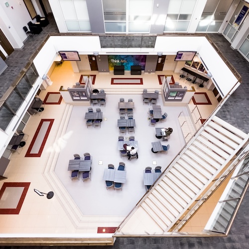 Overhead view of an atrium with several tables and students studying in the centre