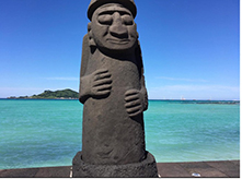 Statue displayed in front of ocean with island in background