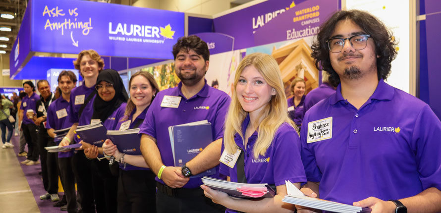 student ambassadors lined up in front of Laurier's OUF booth smiling
